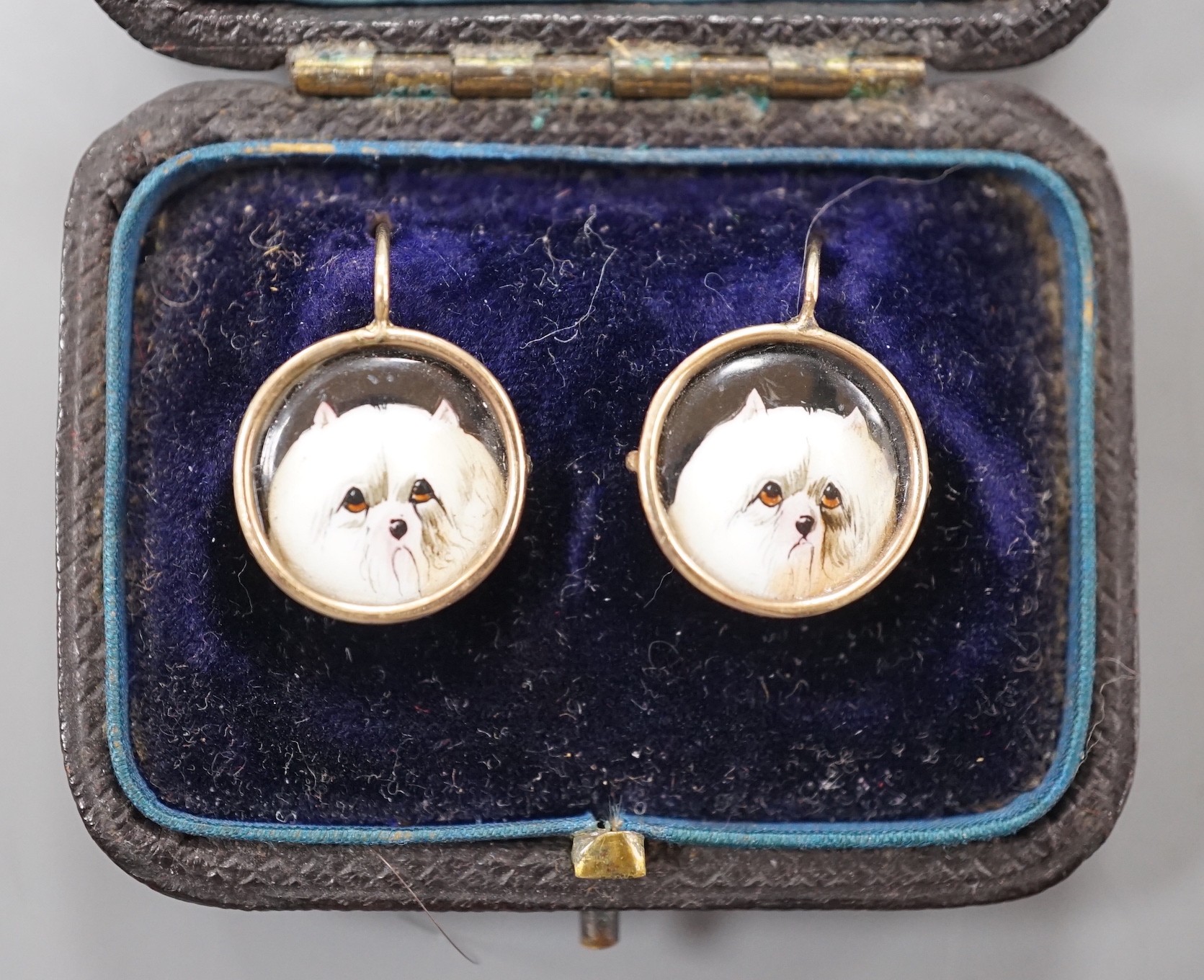 A cased pair of yellow metal and circular enamel earrings, decorated with the heads of a dog, diameter 14mm, gross weight 2.8 grams.